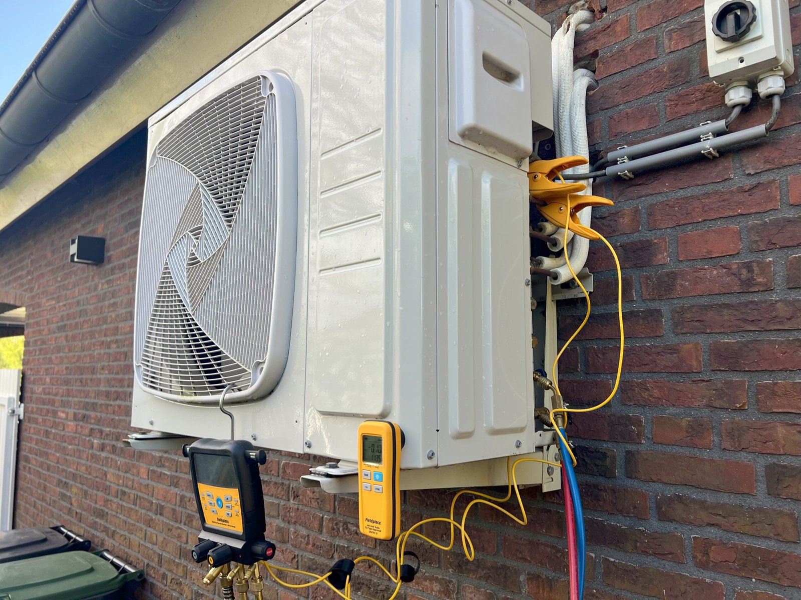 Buitenunit airco met Fieldpiece manifoldmeter tijdens inbedrijfstelling