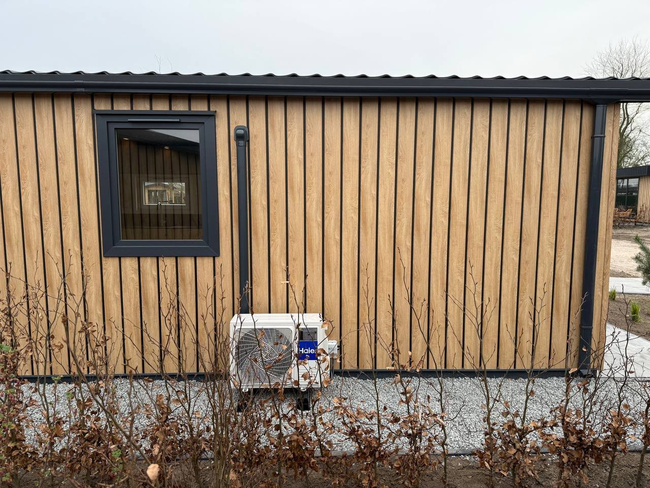 Buitenunit van airco netjes geplaatst naast chalet met verzorgde afwerking